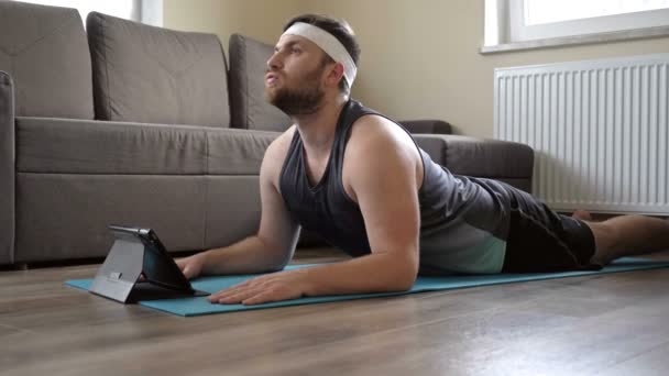 Muž s nadváhou cvičí na podložce. Pandemické čerpadla se potřebují pro virtuální fitness. — Stock video