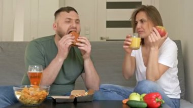 Genç çiftin farklı yeme alışkanlıkları var. Koca fast food yemekten mutlu, karısı ise vejetaryen. Sağlıklı ve sağlıksız beslenme.