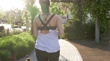 Köpeğiyle koşan atletik görünüşlü bir kadın. Sağlıklı bir yaşam tarzı. Arka plan.