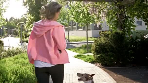 Sportlich aussehende Frau joggt mit ihrem Hund. — Stockvideo