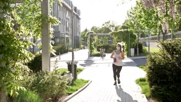 Sport treiben während der Quarantäne. Frau in medizinischer Maske joggt mit ihrem Hund. Gesunder Lebensstil. — Stockvideo