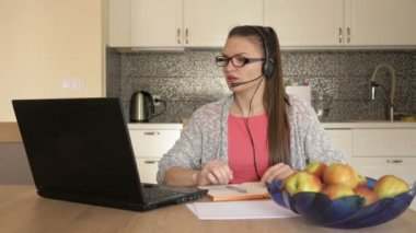 Masada dizüstü bilgisayarı olan genç bir kadın, online müşteri danışmanlığı..