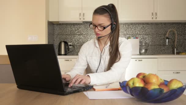 Женщина с наушниками перед ноутбуком за столом, онлайн-консалтинг. Телеработа . — стоковое видео