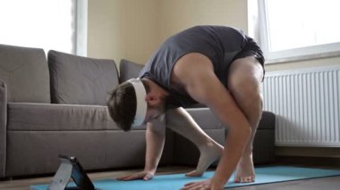 Kilolu adam karmaşık spor egzersizleri yapmaya çalışıyor. Evde spor yapıyorum. Sanal fitness ihtiyacını arttıran salgın..