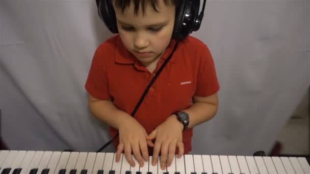 Młody chłopak w słuchawkach gra syntezator Hd — Wideo stockowe