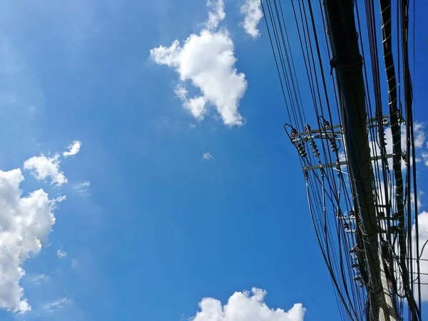 Mavi gökyüzü arka plan üzerinde yüksek gerilim elektrik telleri ve iletişim kablosu elektrik direği — Stok fotoğraf
