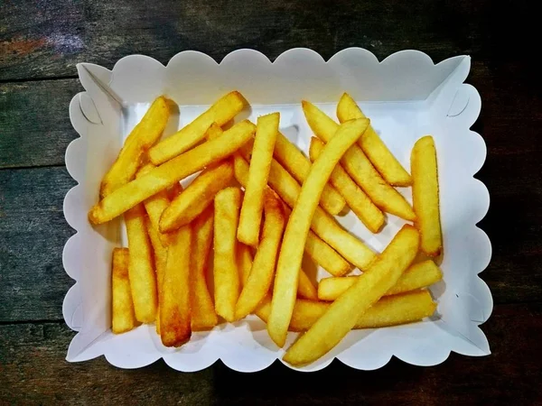 Patates kızartması beyaz bir kap içinde ahşap bir masa yerleştirilen