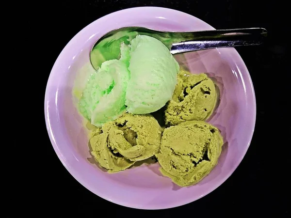 Green tea ice cream and Lemon ice cream In a cup on a black background