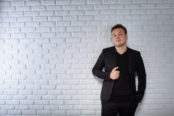 Man in black suite and black t-short near the white wall