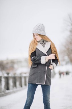 Sokakta poz güzel mutlu gülümseyen kız. Yüz dokunmadan uzun saçları ile oynarken modeli. Şık giysiler giyen kadın. Kış tatil kavramı. Sihirli kar yağışı etkisi