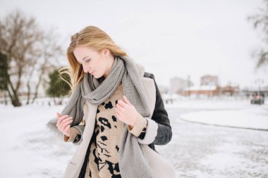 Sokakta poz güzel mutlu gülümseyen kız. Yüz dokunmadan uzun saçları ile oynarken modeli. Şık giysiler giyen kadın. Kış tatil kavramı. Sihirli kar yağışı etkisi
