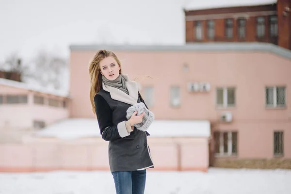 Jeune belle fille souriante heureuse posant dans la rue. Modèle jouant avec ses cheveux longs, toucher le visage. Femme portant des vêtements élégants. Concept vacances d'hiver. Effet de neige magique — Photo