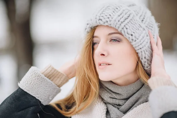 Joven hermosa chica sonriente feliz posando en la calle. Modelo jugando con su pelo largo, tocando la cara. Mujer vestida con ropa elegante. Concepto de vacaciones de invierno. Efecto mágico nevada —  Fotos de Stock