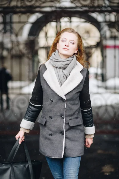 Jovem bela menina sorridente feliz posando na rua. Modelo brincando com seu cabelo comprido, tocando o rosto. Mulher vestindo roupas elegantes. Conceito de férias de inverno. Efeito de neve mágico — Fotografia de Stock