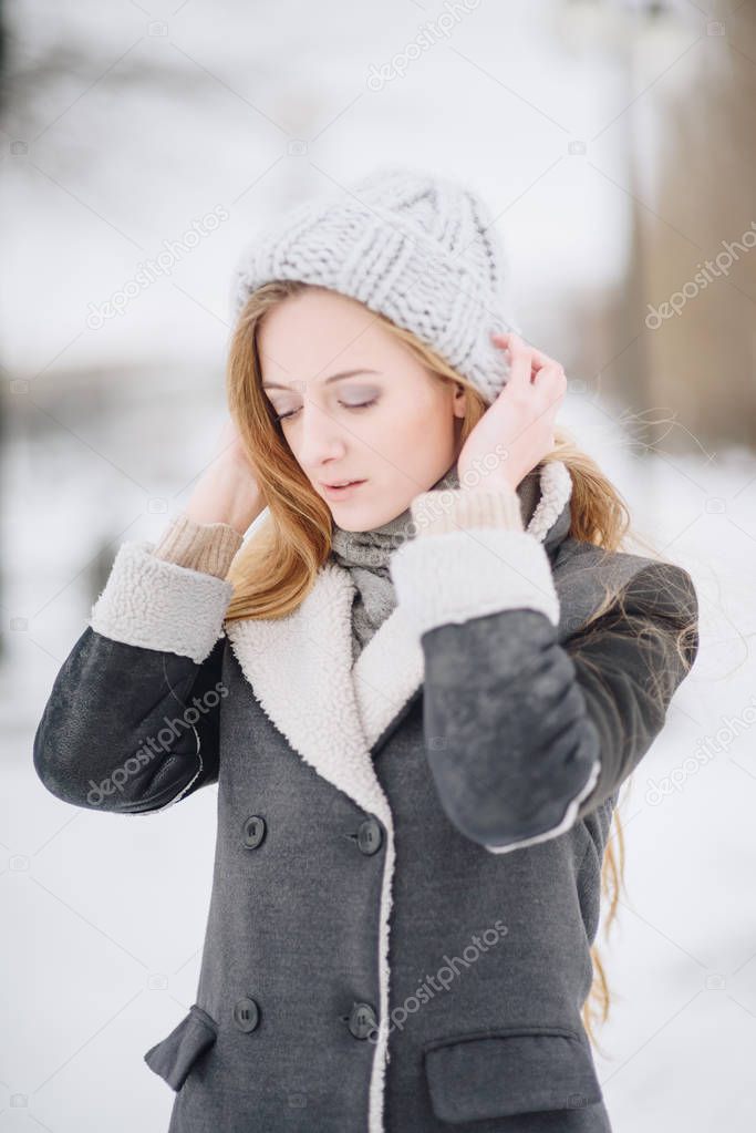 Young beautiful happy smiling girl posing on street. Model playing with her long hair, touching face. Woman wearing stylish clothes. Winter holidays concept. Magic snowfall effect
