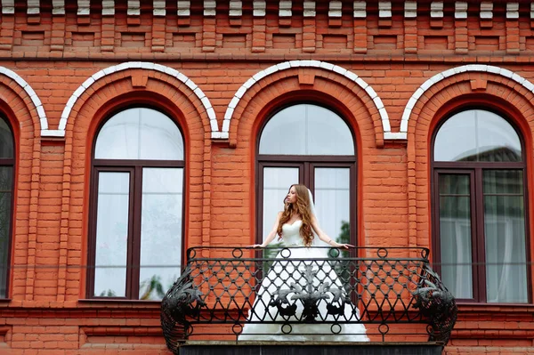 빨간 호텔 건물에 고급 아파트의 발코니에 웨딩 드레스 신부 — 스톡 사진