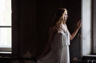 Genç güzel kız portresi kapalı yaz. Güzel bir kadın iki peri masalı windows ahşap dolap, izleri eski kale içinde yanında poz. Gelin beyaz atlas elbiseli. Fotoğraf bir model vardır.