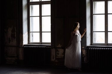 Genç güzel kız portresi kapalı yaz. Güzel bir kadın iki peri masalı windows ahşap dolap, izleri eski kale içinde yanında poz. Gelin beyaz atlas elbiseli. Fotoğraf bir model vardır.