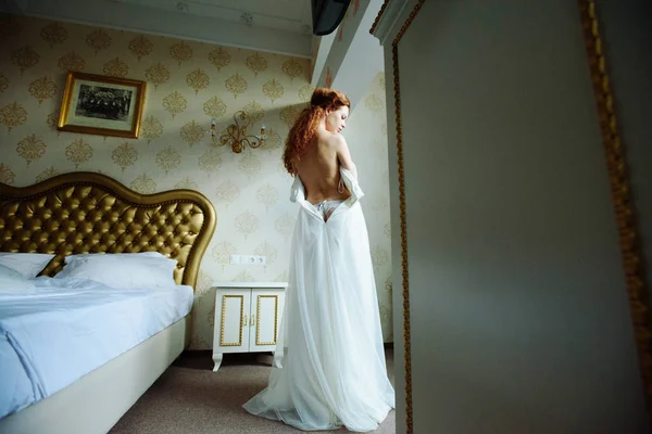Beautiful sexy redhair lady in elegant white wedding dress. Fashion portrait of model indoors. Beauty woman spin. Female body and ass in underwear. Close up naked girl. — Stock Photo, Image
