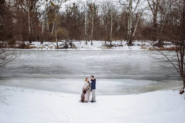 Elegante bella giovane coppia sposa e sposo in piedi sullo sfondo di un fiume paesaggio invernale . — Foto Stock