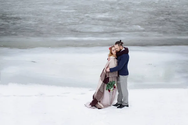 Elegante bella giovane coppia sposa e sposo in piedi sullo sfondo di un fiume paesaggio invernale . — Foto Stock