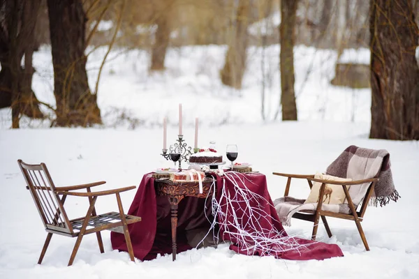 Top view of a table with dread and cookies baskets  candles, two chairs covered  white snow on the background. — Stock Photo, Image