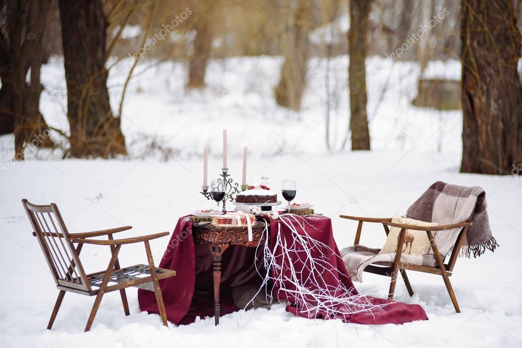 Top view of a table with dread and cookies baskets  candles, two chairs covered  white snow on the background.