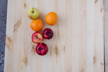 Taze kırmızı ve yeşil elma, ahşap güverte üzerinde turuncu.