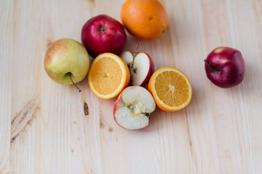 Taze kırmızı ve yeşil elma, ahşap güverte üzerinde turuncu.