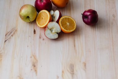Taze kırmızı ve yeşil elma, ahşap güverte üzerinde turuncu.