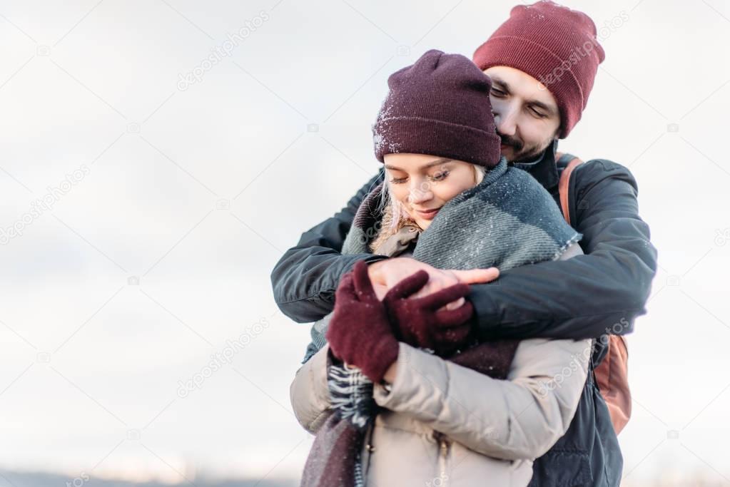 Young hipster couple hugging each other in winter park.