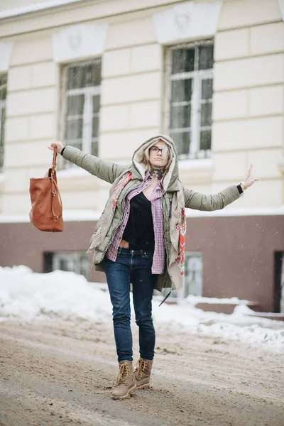 Outdoor portrait of young beautiful happy girl posing on street. Model wearing stylish warm clothes. Magic snowfall. Winter holidays concept. City lifestyle. Waist up. Color — Stock Photo, Image