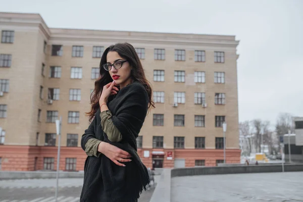 Fashion consept: beatiful giovane ragazza con i capelli lunghi, occhiali, labbra rosse in piedi vicino alla parete moderna indossa in abito verde e jeans grigi. Voleva parlare al telefono. . — Foto Stock