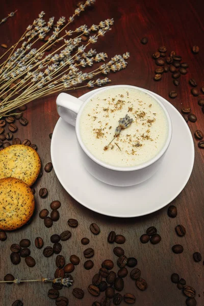 Cup of coffee with milk, pussy-willow and dried branches and leaves at brown background.