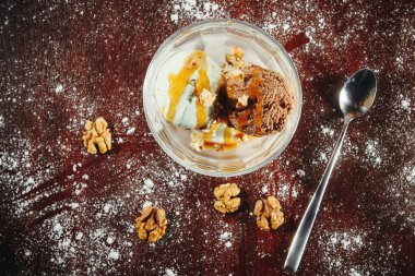 Ev yapımı çikolatalı dondurma ile ahşap bir masa üzerinde bir cam kase kıyılmış fıstık fıstık ezmesi ile serpin.