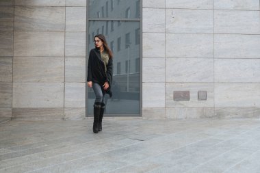 Moda consept: güzel uzun saçlı genç kız gözlük, yeşil takım ve gri kot modern duvarının yakınında duran kırmızı dudaklar. Evet istedi.