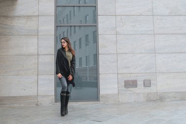Moda consept: güzel uzun saçlı genç kız gözlük, yeşil takım ve gri kot modern duvarının yakınında duran kırmızı dudaklar. Evet istedi.
