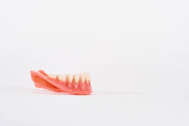 Sahte protezler. Diş hijyenisti konsepti. Alt çenenin tam çıkarılabilir plastik protezi.