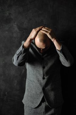 Portrait of handsome business man.Concept of fear, shame, domestic violence. Man covers his head his hands on light scratched background.