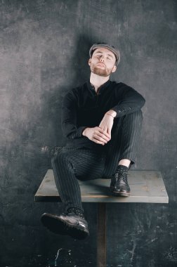 Satisfaction Portrait of man with a beard, sitting on table.