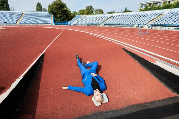 Sleep time. Lazy man sleeps tired lies on the track in the stadium.