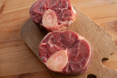 İki parçalı yatay fotoğraf ya da üzerinde birkaç damla kan ve et olan büyük bir kemik parçası. Kemikler masaya konur..