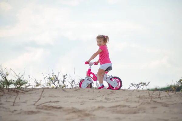 Little girl riding a balance bike on bicycle lane in the outdoor countryside