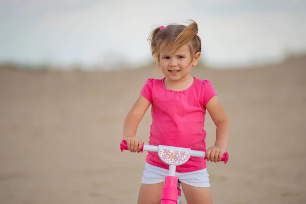 Little girl riding a balance bike on bicycle lane in the outdoor countryside