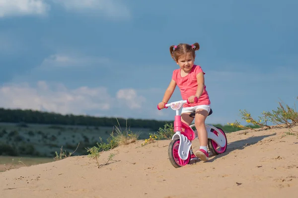 Little girl riding a balance bike on bicycle lane in the outdoor countryside