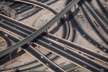 Dubai, BAE 'deki karmaşık bir otoyol kavşağının ve metro hattının havadan görüntüsü. Çölde trafik, arabalar ve üstgeçitlerle modern yol altyapısı.