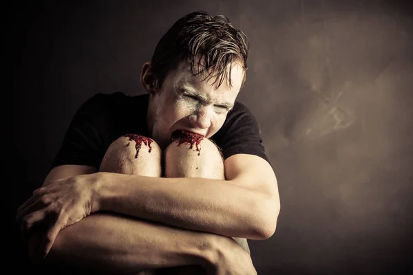 Psychotic and angry teen chews his knees — Stock Photo, Image