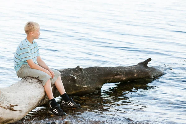 Αγόρι κάθεται σε ένα ξύλο που επιπλέει — Φωτογραφία Αρχείου