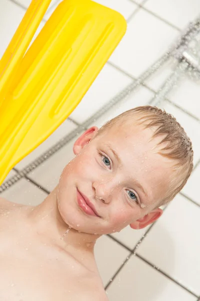 Boy in shower holding paddles from boat — Stockfoto