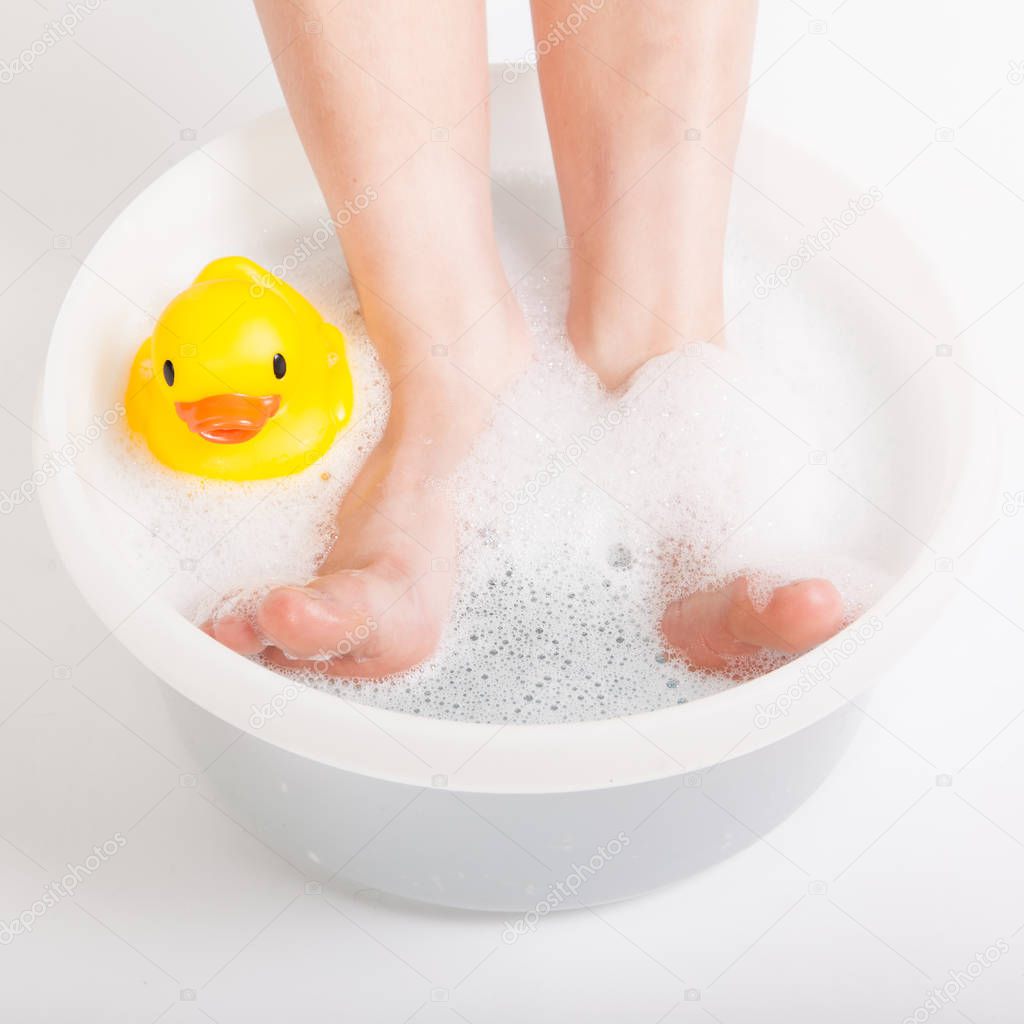 Boy feet in food bath with rubber duck